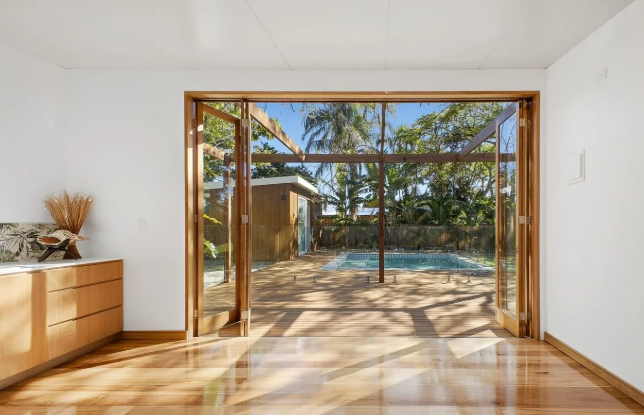 Bright living room with timber bi-fold doors opening to a pool deck